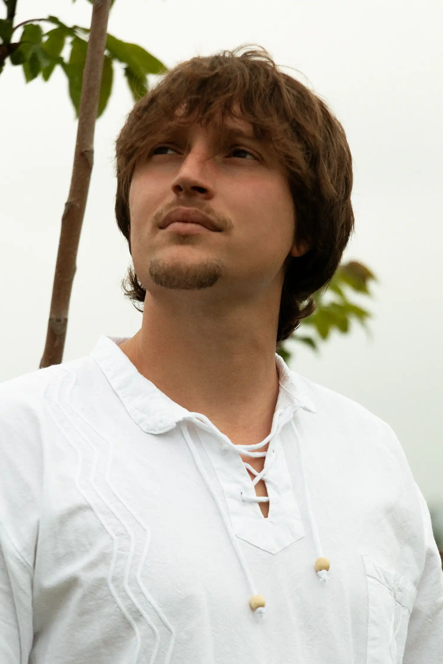 Modelo masculino con camisa ibicenca de hombre blanca entre vegetación vista detalle del cuello.