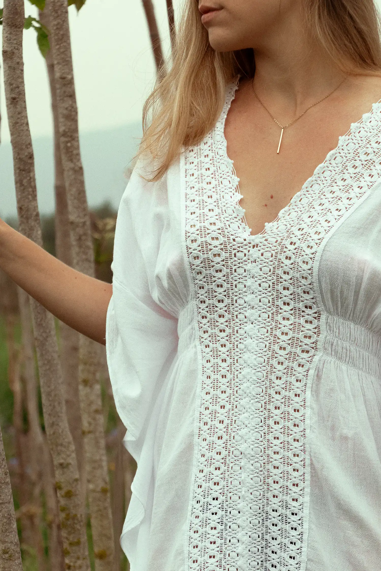 Modelo femenina con caftán ibicenco blanco en el campo vista de detalle