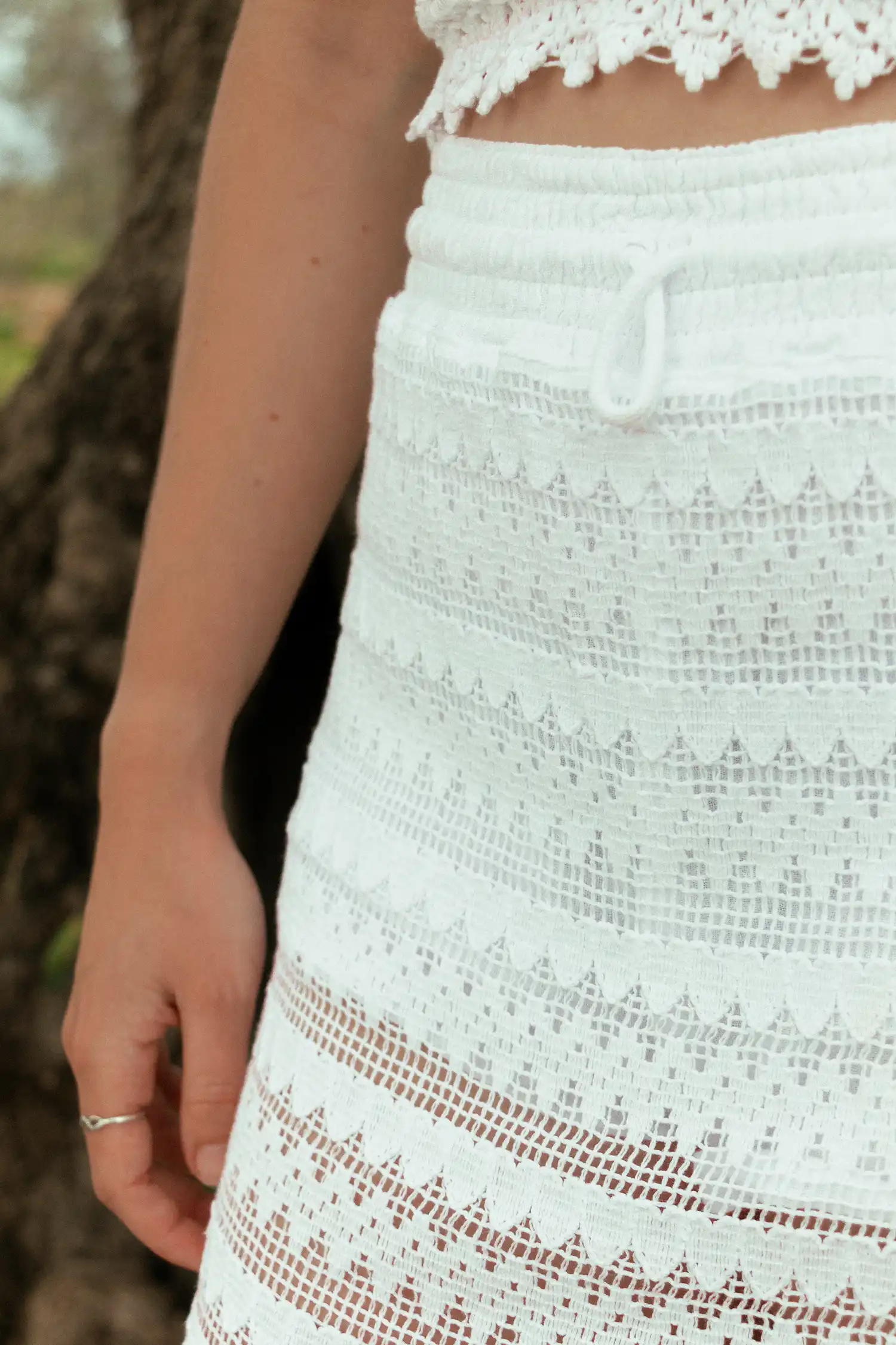 Modelo femenina con una falda ibicenca blanca en el campo vista detalle