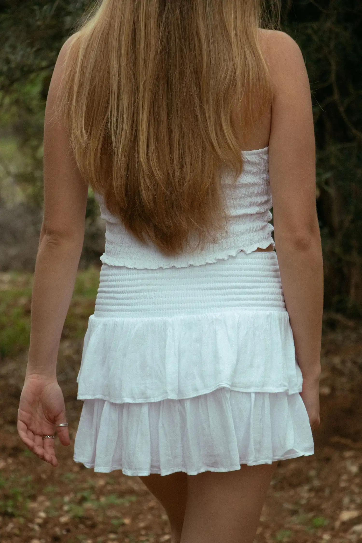 Modelo femenina con una falda ibicenca blanca en el campo vista trasera