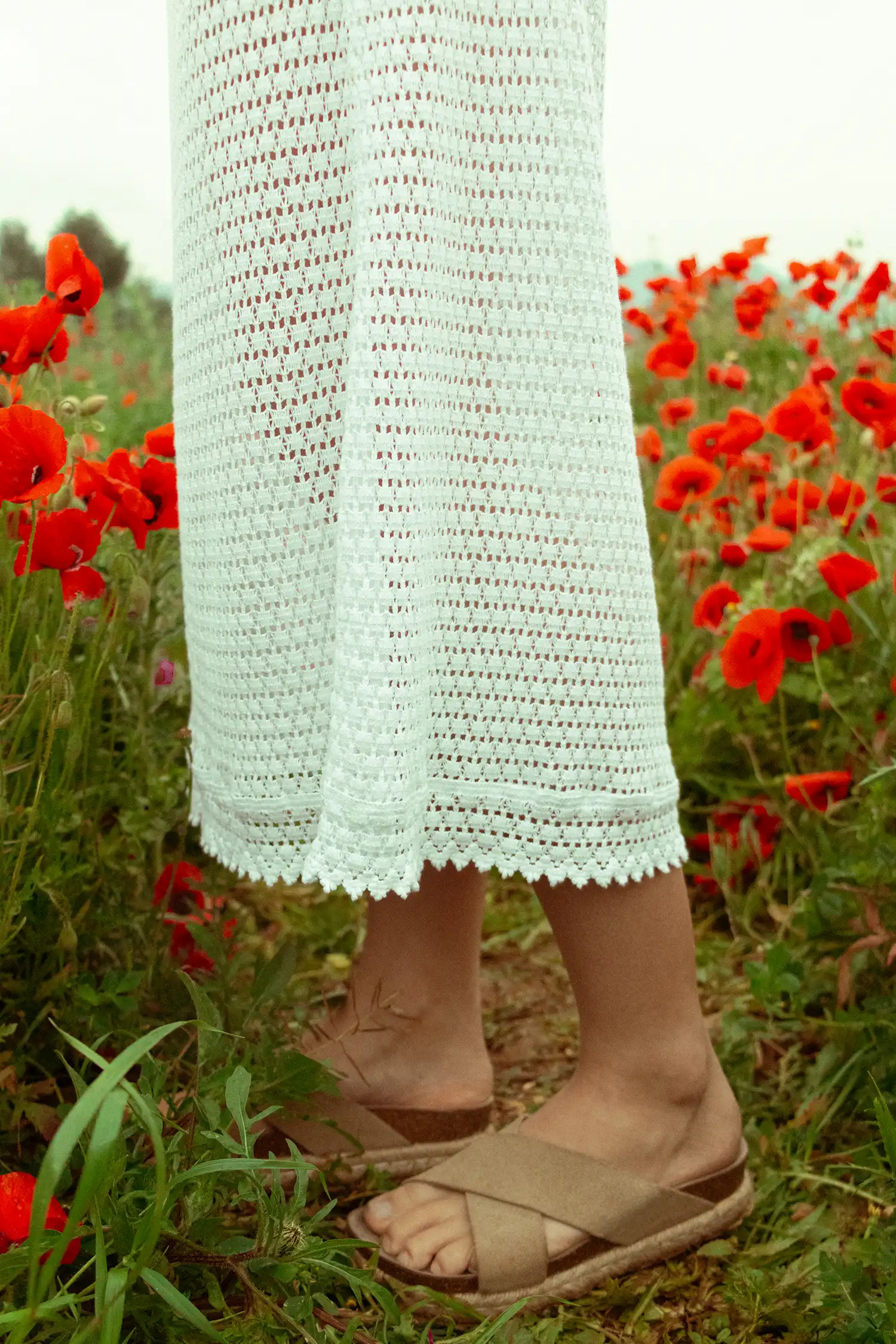 Modelo femenina con una falda larga ibicenca blanca en un campo de flores con vista detalle de la falda
