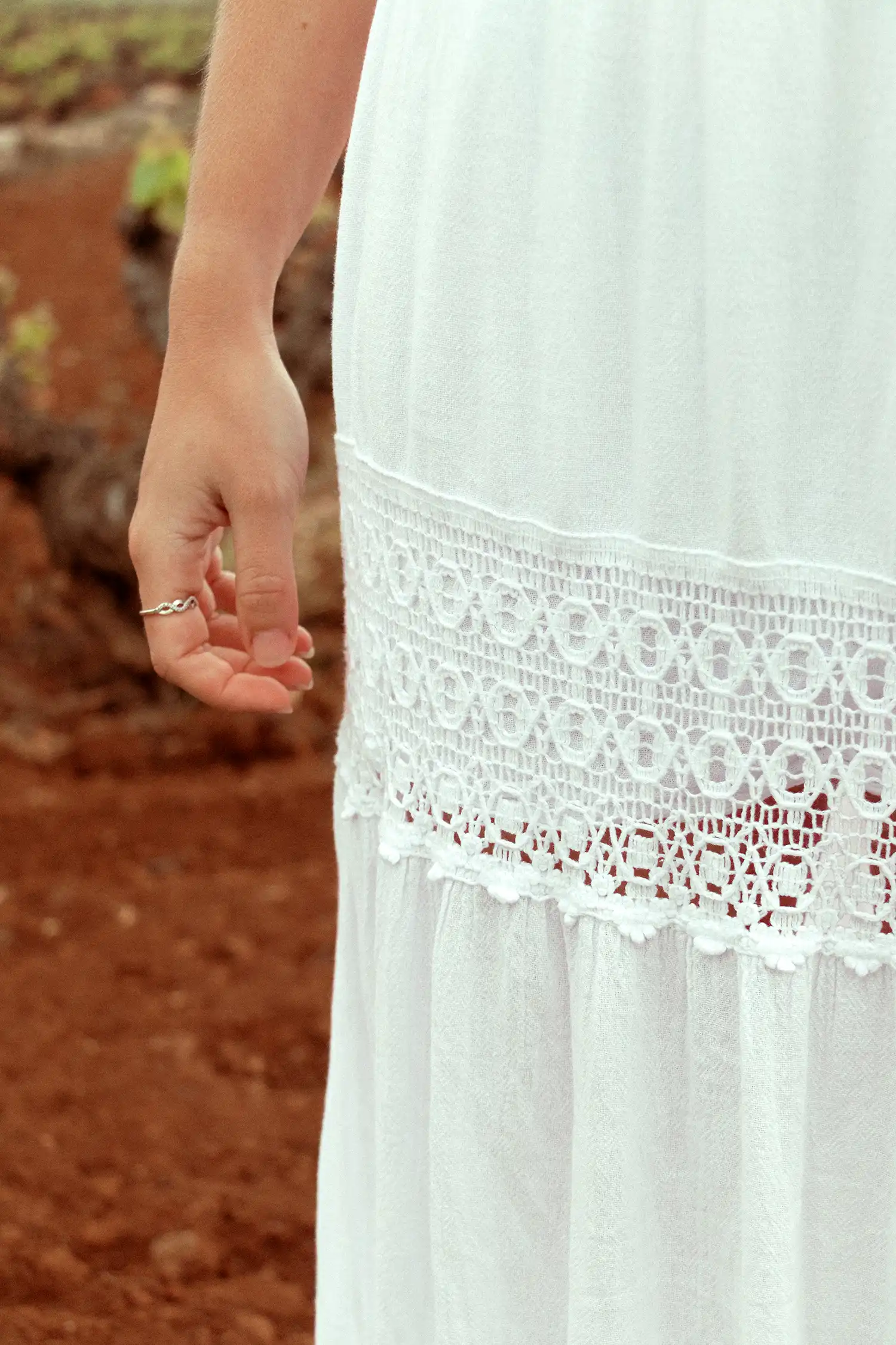 Modelo femenina con una falda larga ibicenca blanca en un campo con vista detalle de la falda