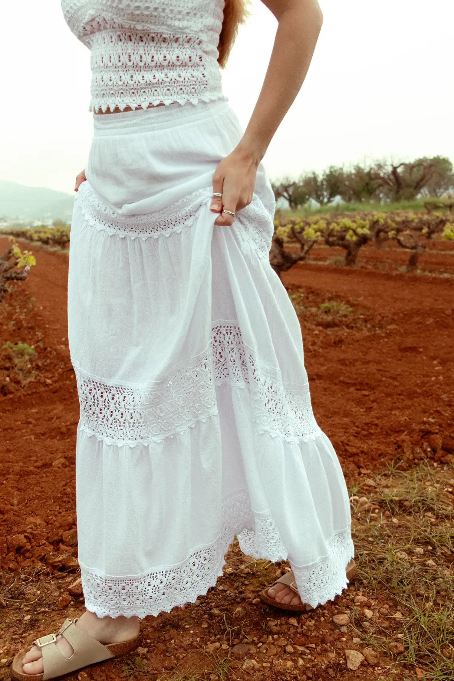 Modelo femenina con una falda larga ibicenca blanca en un campo con vista ampliada