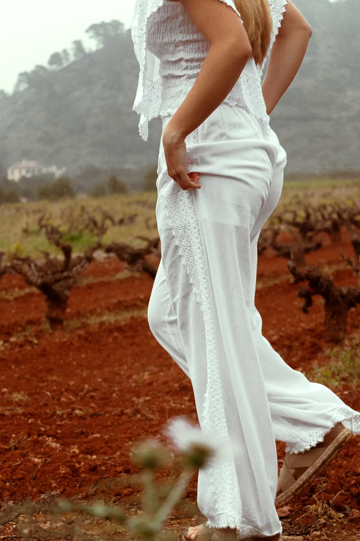 Pantalón ibicenco de mujer blanco en un campo de viñas, vista trasera