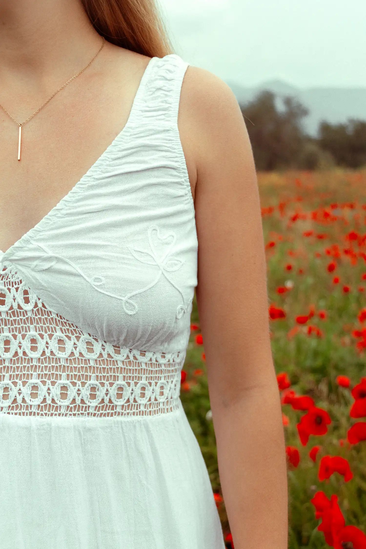 Modelo femenina con vestido ibicenco corto blanco en un campo de flores vista detalle