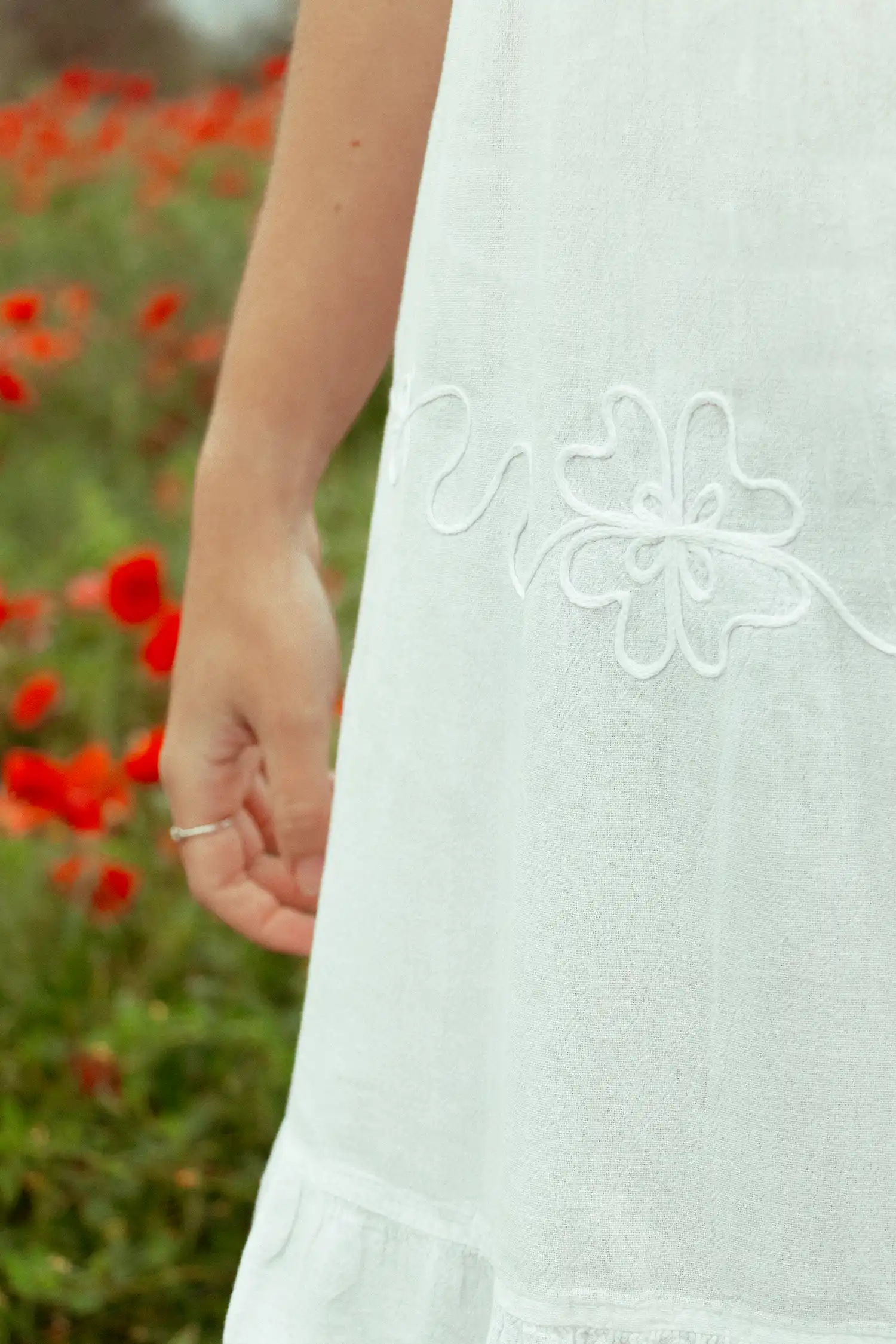 Modelo femenina con vestido ibicenco corto blanco en un campo de flores vista detalle