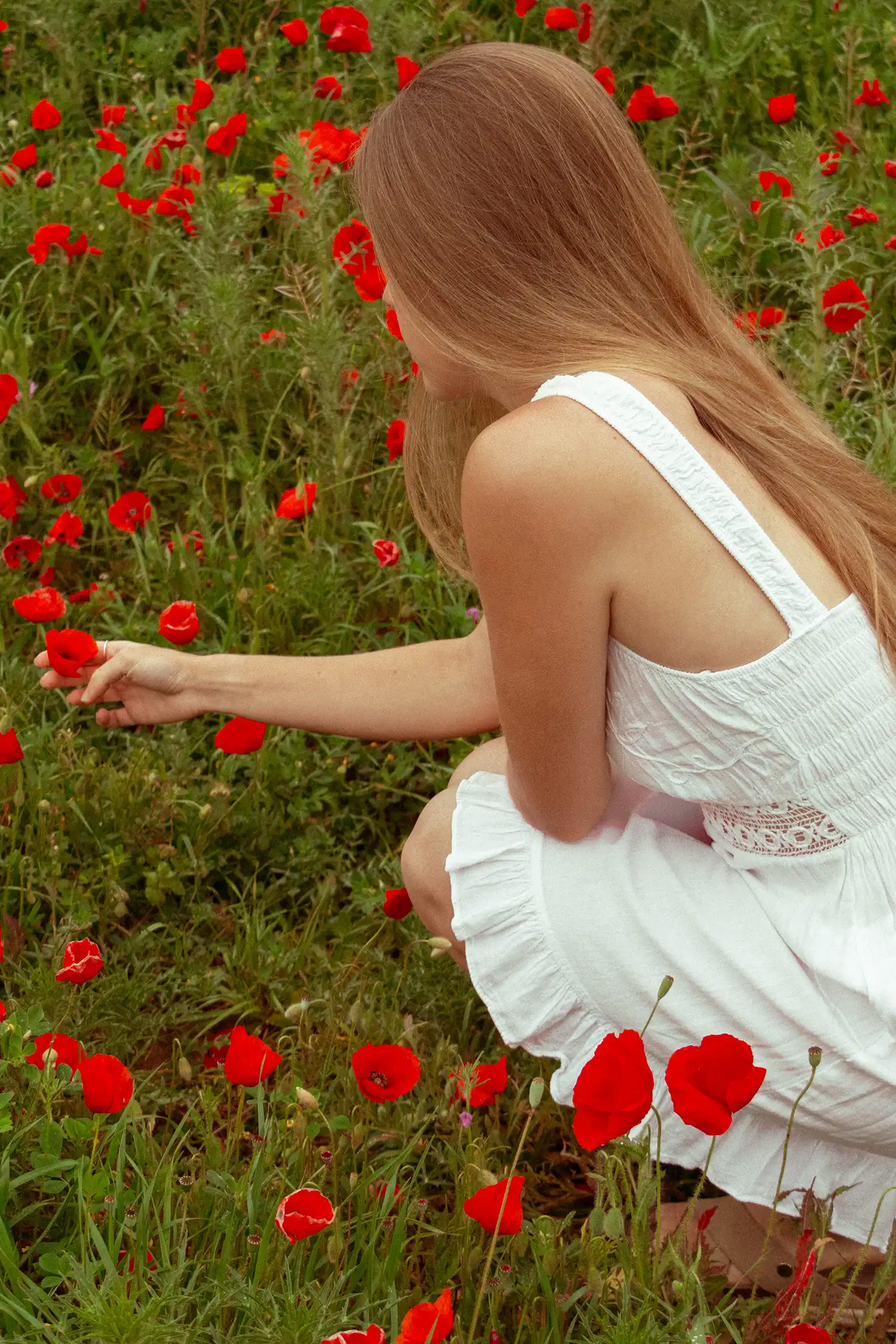 Modelo femenina con vestido ibicenco corto blanco en un campo de flores
